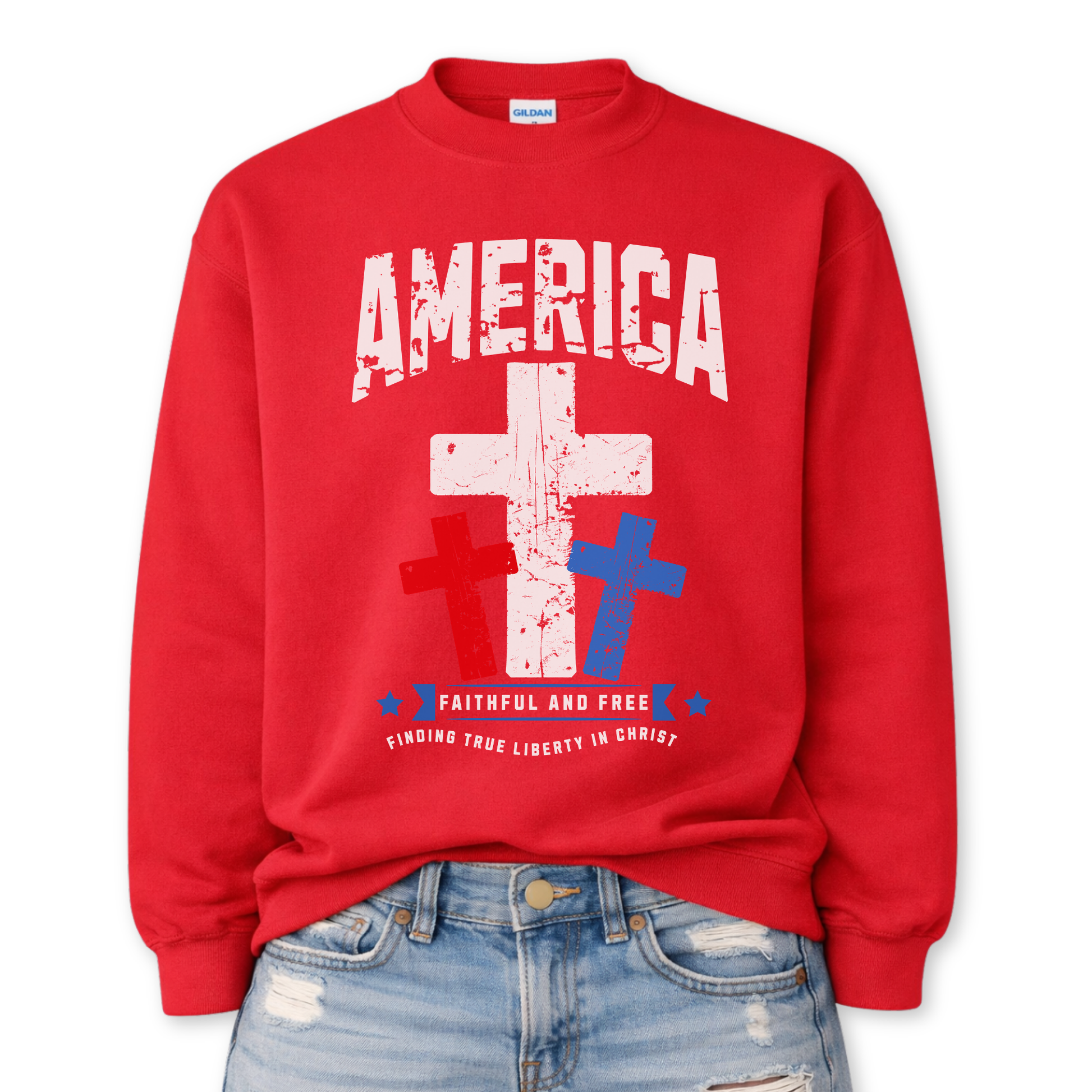Christian patriotic faith graphic on a red sweatshirt. The design features a bold distressed “America” arch across the chest with a large central white cross, flanked by red and blue crosses below for a strong USA color story. A banner reading “Faithful and Free” anchors the design, with smaller text noting “Finding True Liberty in Christ,” blending faith-forward messaging with classic Fourth of July patriotic style.