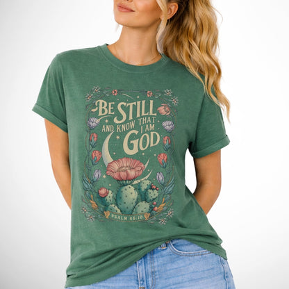 Be still and know that I am God Psalm 46:10 .  an oversized blooming cactus plant on  an light green comfort colors tee