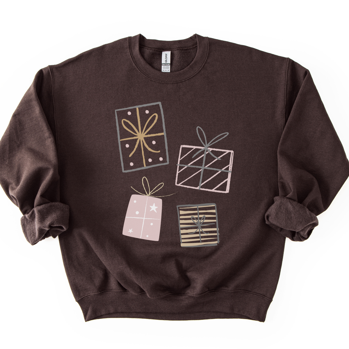 A festive Christmas graphic featuring stacked presents in soft gray, pink, and gold tones on a brown sweatshirt