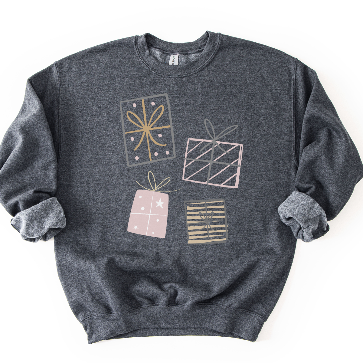 A festive Christmas graphic featuring stacked presents in soft gray, pink, and gold tones on a heather gray sweatshirt