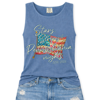 Blue Jean Comfort Colors tank top featuring a patriotic American flag graphic with mixed stripe patterns and script text reading “Stars, Stripes & Indiana nights” with “1776–2026” underneath, styled with light wash denim jeans.