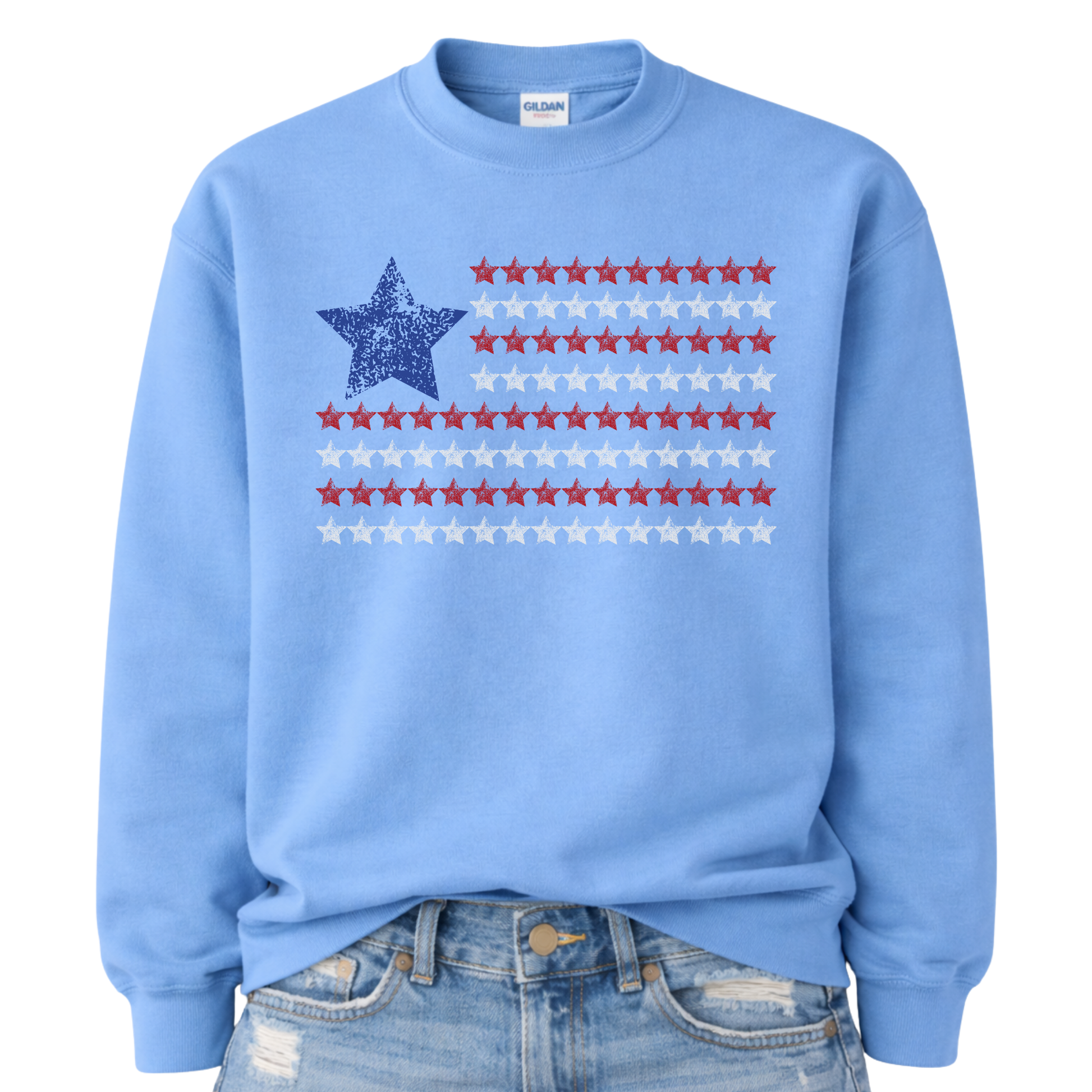 Patriotic Americana flag graphic on a blue sweatshirt. The design features a distressed blue star at the top left with horizontal rows of red stars creating a flag-inspired layout. The worn, vintage texture gives it an easy Americana look while staying clean and bold for everyday wear. A simple patriotic staple for Fourth of July, summer holidays, and USA-themed seasonal collections.