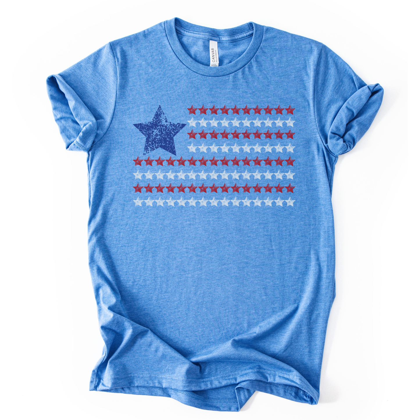 Patriotic Americana flag graphic on a blue t-shirt. The design features a distressed blue star positioned at the top left, paired with horizontal rows of red stars forming a flag-inspired layout. Soft weathered textures give the graphic a vintage, worn-in look while keeping the overall style clean and modern. The simple star-based flag design makes this an easy, everyday patriotic piece for Fourth of July, summer holidays, and Americana-themed collections.
