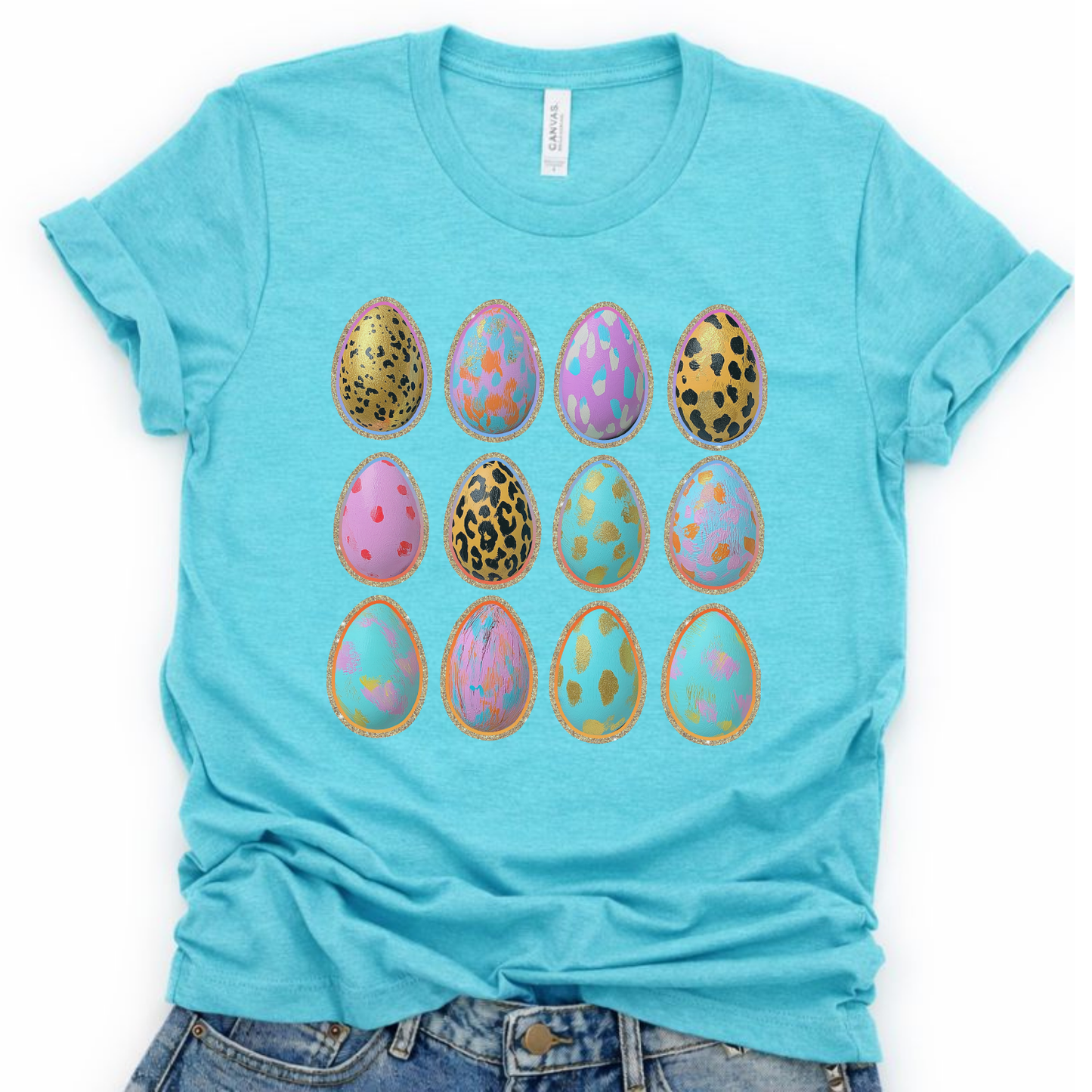 A graphic t-shirt printed on a Bella Canvas® premium aqua color tee.

The graphic features a grid of illustrated Easter eggs, each decorated with mixed patterns including leopard spots, soft florals, abstract brush textures, and pastel accents. The eggs are outlined with a subtle metallic-style border, creating a playful, modern Easter look that feels bright, and fun.
