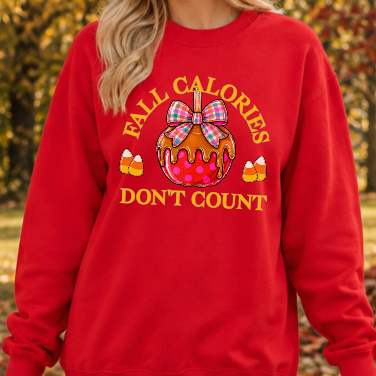 Fall calories don't count featuring a cute candy apple with a fall plaid ribbon. Cute little candy corns accent the sides of the large candy apple. Red sweatshirt