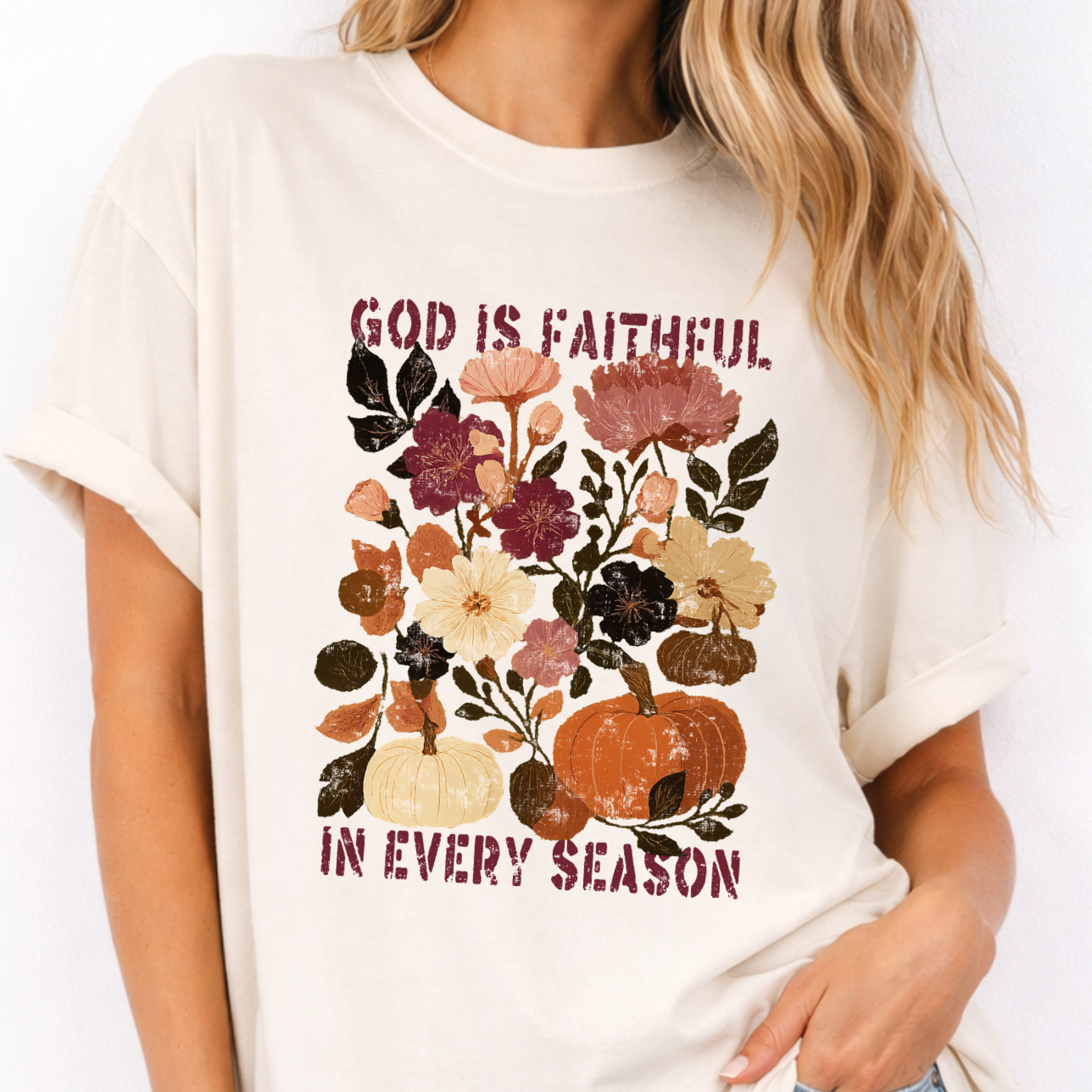 Person wearing a white t-shirt with floral and pumpkin design and text 'GOD IS FAITHFUL IN EVERY SEASON'.