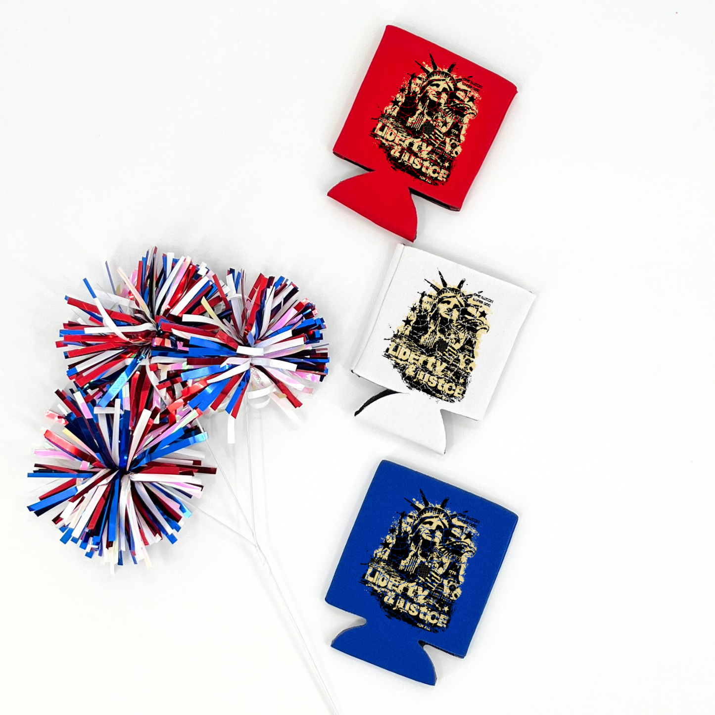 Assorted collapsible can coolers in red, white, and royal blue displayed with red, white, and blue metallic pom poms. The graphic features a distressed Statue of Liberty design with bold wording that reads “Liberty Justice” printed on the front of the drink sleeve style can coolers.