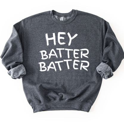 Dark heather gray crewneck sweatshirt with white hand-drawn style lettering reading “Hey Batter Batter,” styled flat with sleeves scrunched
