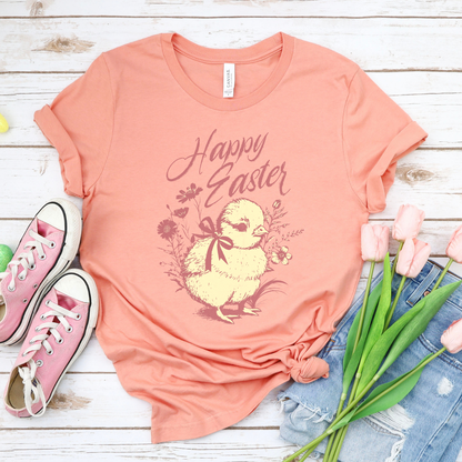 Heather Sunset Easter seasonal graphic on a Bella Canvas t-shirt. The design features a vintage-inspired illustration of two children dressed in bunny outfits gathered around a rabbit with pastel Easter eggs and soft greenery. The phrase “May the gifts of Easter bring you hope that grows” curves above the artwork in delicate script lettering, creating a nostalgic, heartfelt spring message.