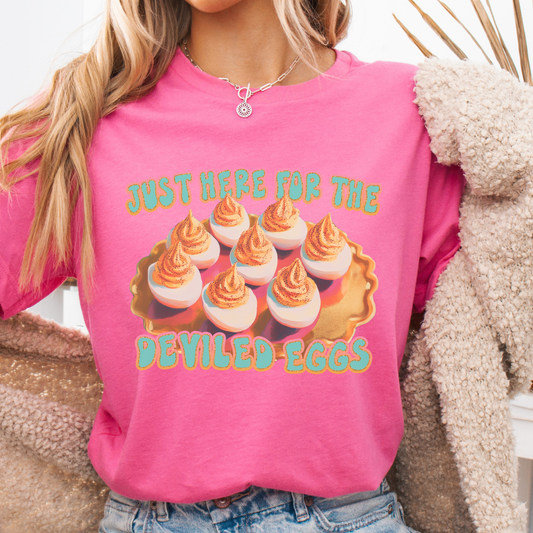 Person wearing a pink shirt with a graphic of deviled eggs and text.  Just here for the deviled eggs
