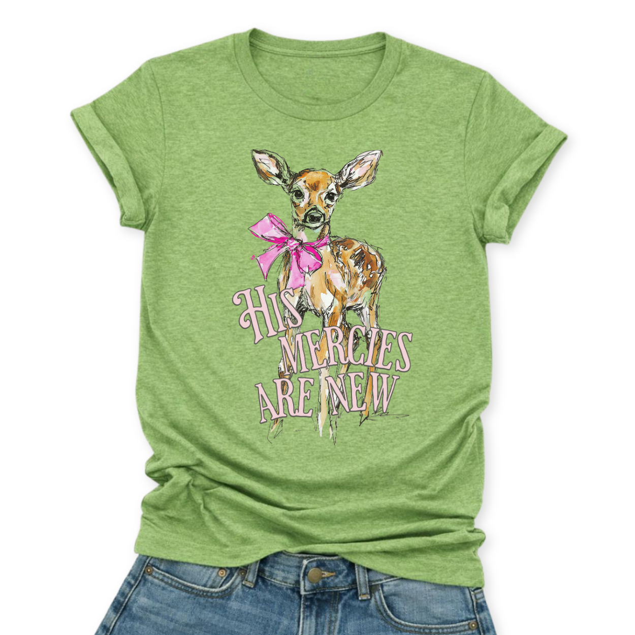 Christian Easter scripture graphic on a Bella Canvas t-shirt. The design features an illustrated fawn with soft watercolor-style detailing, accented with a bright pink bow for a feminine spring touch. The phrase “His Mercies Are New” appears in vintage-inspired lettering beneath the deer, referencing Lamentations 3:23 and the renewal message of Easter.