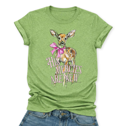 Christian Easter scripture graphic on a Bella Canvas t-shirt. The design features an illustrated fawn with soft watercolor-style detailing, accented with a bright pink bow for a feminine spring touch. The phrase “His Mercies Are New” appears in vintage-inspired lettering beneath the deer, referencing Lamentations 3:23 and the renewal message of Easter.