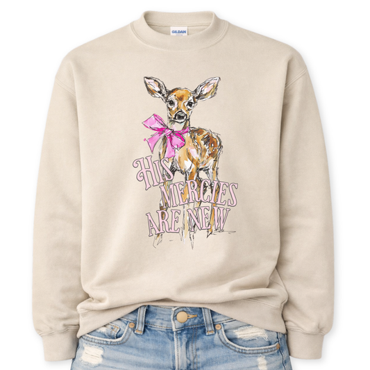 Beige Bold Christian Easter graphic on a Gildan crewneck sweatshirt. The design features a hand-illustrated fawn with a pink bow, paired with the phrase “His Mercies Are New” in a soft vintage-style font. The artwork blends feminine spring tones with a meaningful scripture-inspired message, creating a standout seasonal piece for Easter