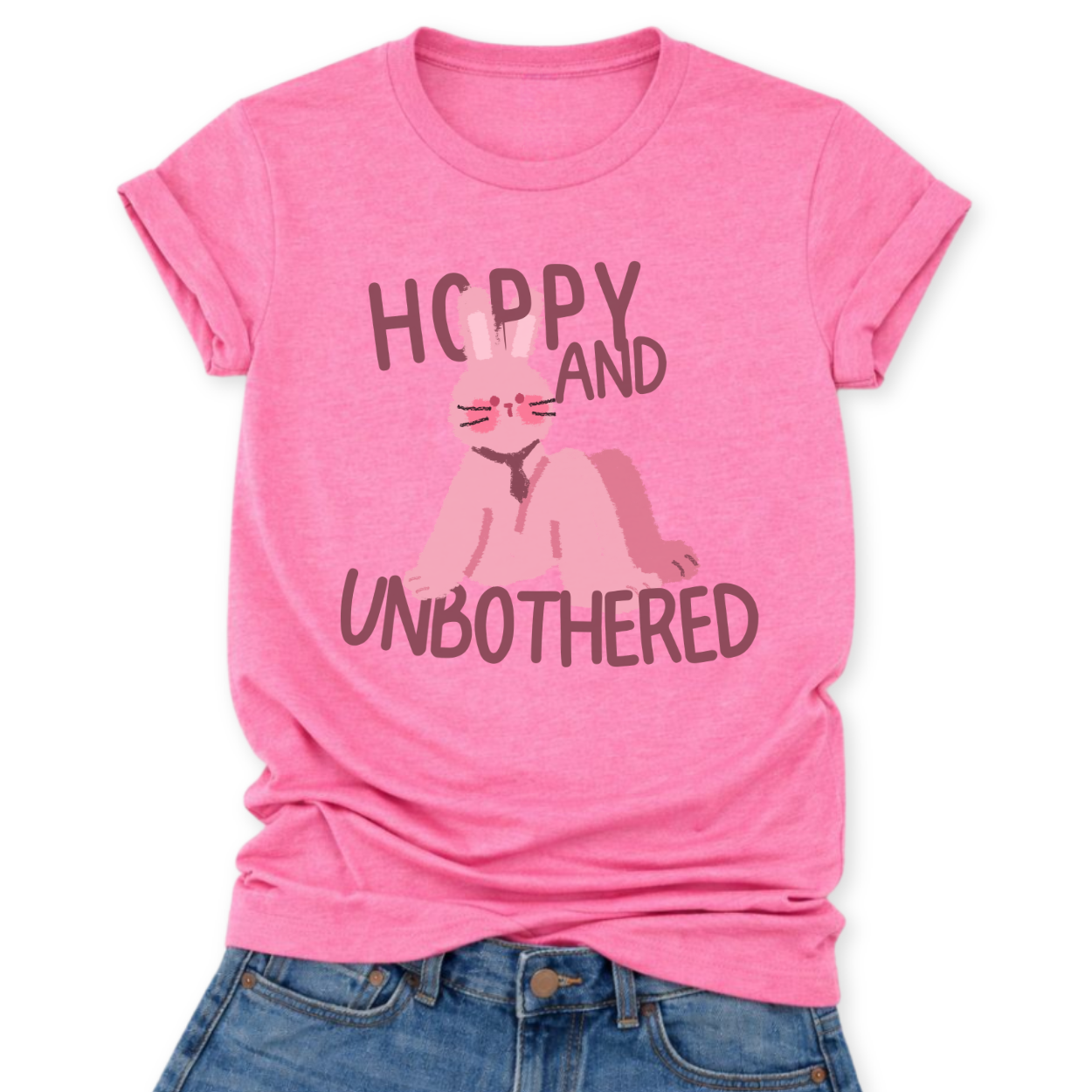 Heather Charity Pink Playful Easter graphic on a Bella Canvas t-shirt. The design features a relaxed pink bunny illustration paired with the bold phrase “Hoppy and Unbothered” in modern, oversized lettering. The artwork blends trendy humor with soft seasonal styling, making it a fun spring statement piece.