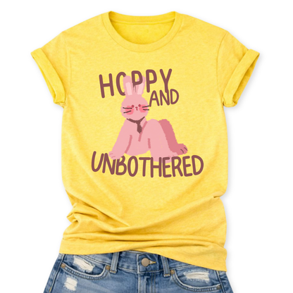 Heather Yellow Playful Easter graphic on a Bella Canvas t-shirt. The design features a relaxed pink bunny illustration paired with the bold phrase “Hoppy and Unbothered” in modern, oversized lettering. The artwork blends trendy humor with soft seasonal styling, making it a fun spring statement piece.