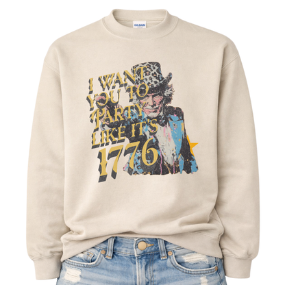 Patriotic Uncle Sam graphic on a tan sweatshirt. The design features a distressed illustrated portrait of Uncle Sam wearing a patterned top hat, paired with bold vintage-style text reading “I Want You to Party Like It’s 1776.” Layered textures, muted patriotic tones, and worn ink details give the artwork a retro Americana feel. A bold, playful patriotic design suited for Fourth of July, summer celebrations, and USA-themed seasonal collections.