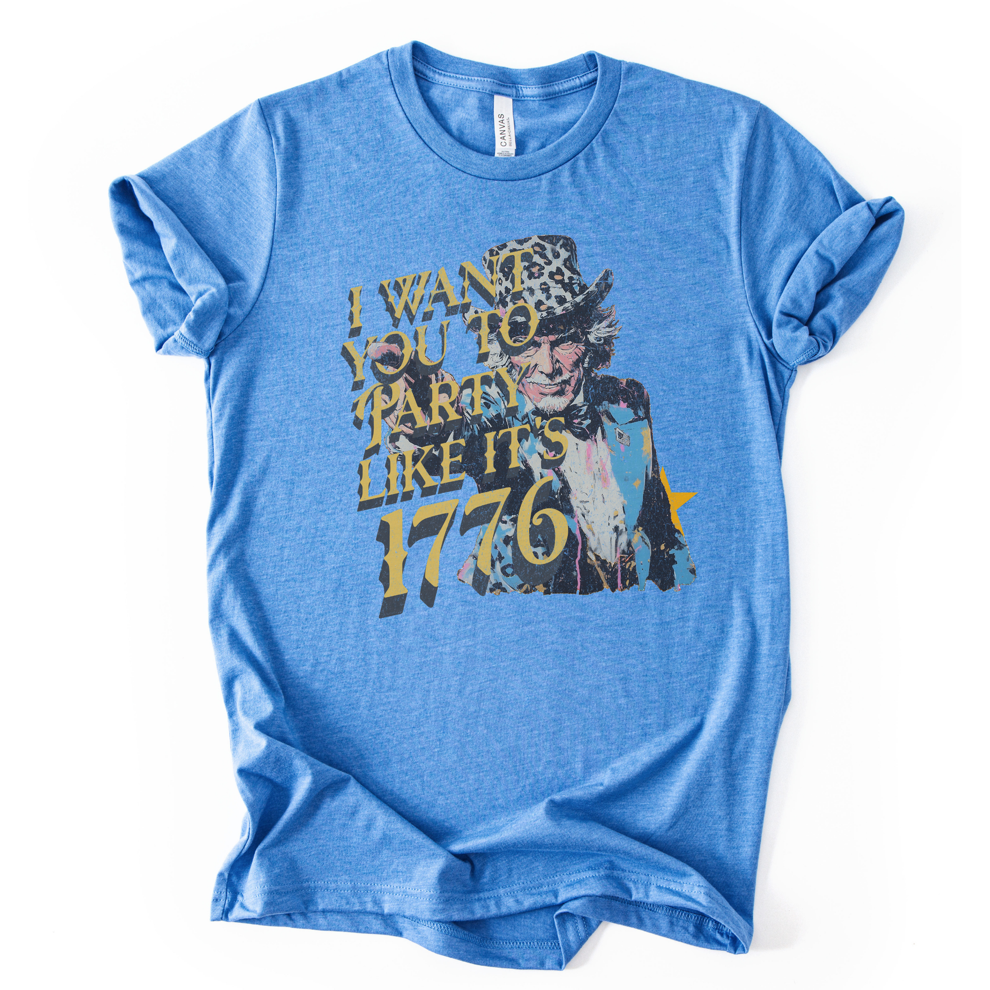 Vintage patriotic 1776 graphic on a blue t-shirt. The design features an illustrated Uncle Sam portrait with distressed textures and bold gold lettering reading “I Want You to Party Like It’s 1776.” The artwork blends Revolutionary War imagery with modern, playful Fourth of July messaging, creating a nostalgic Americana look ideal for Independence Day and summer patriotic collections.