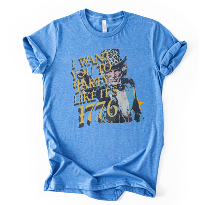 Vintage patriotic 1776 graphic on a blue t-shirt. The design features an illustrated Uncle Sam portrait with distressed textures and bold gold lettering reading “I Want You to Party Like It’s 1776.” The artwork blends Revolutionary War imagery with modern, playful Fourth of July messaging, creating a nostalgic Americana look ideal for Independence Day and summer patriotic collections.