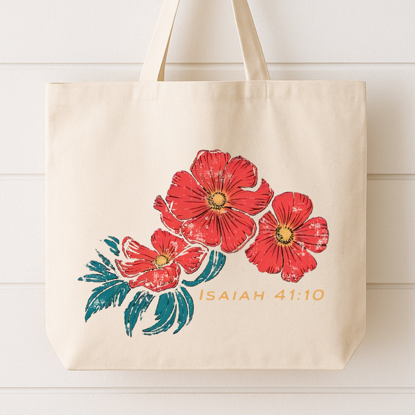 Beige tote bag with red flowers and 'Isaiah 41:10' text on a white wooden background