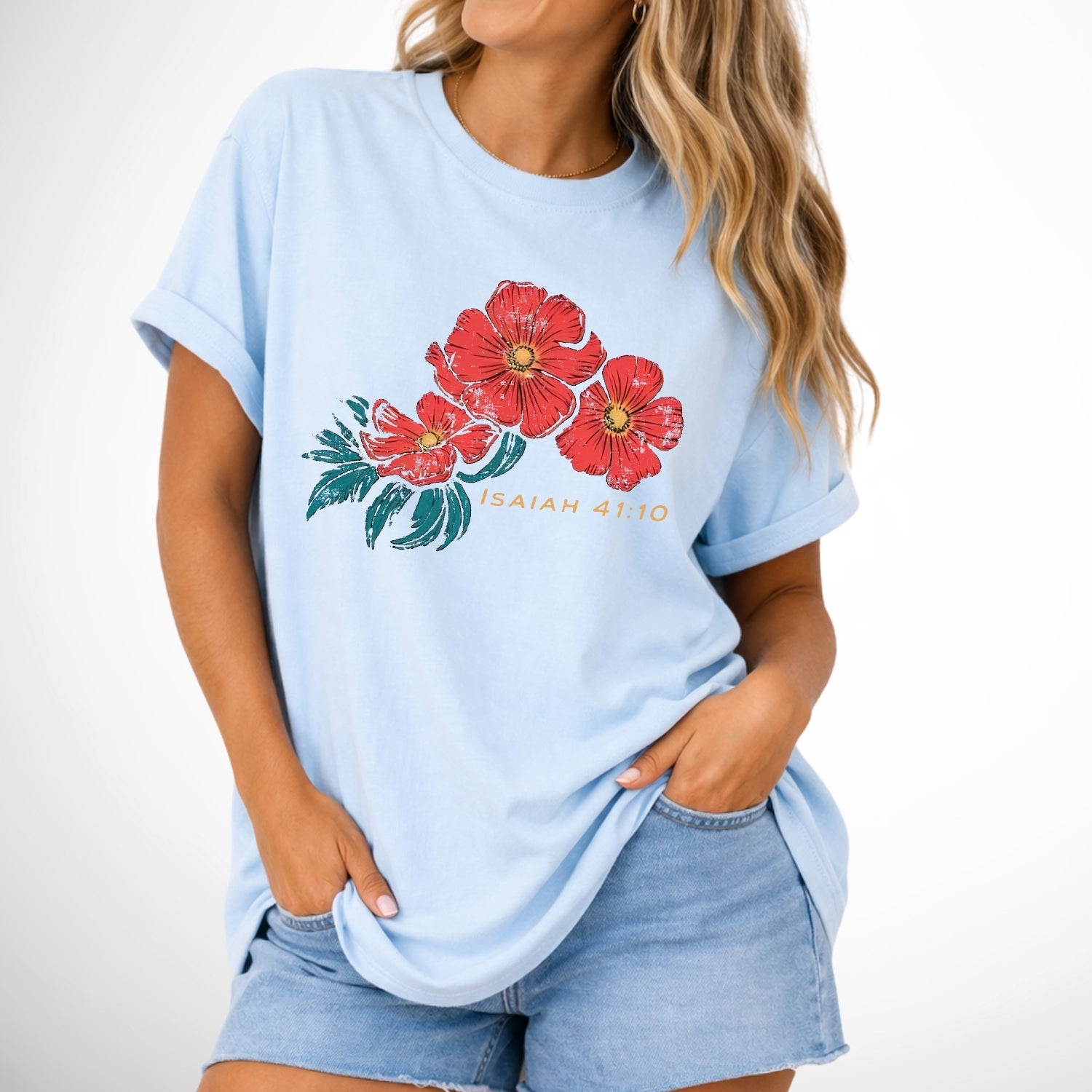 Light blue t-shirt with red floral design and text worn by a person on a white background. Isaiah 41:10 Red Poppy Flowers Graphic Comfort Colors Tee