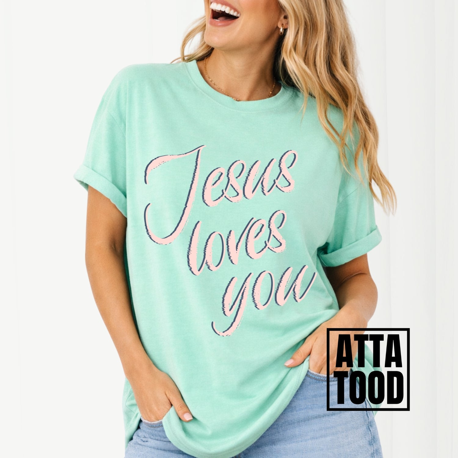 Person wearing a island reef green t-shirt with 'Jesus loves you' text, brand 'ATTA TOOD' visible. Jesus loves you