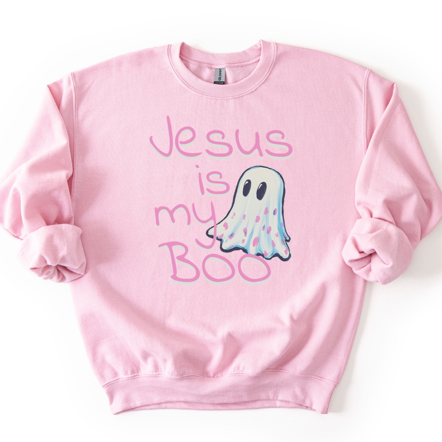 A light pink crewneck sweatshirt featuring a graphic print of a cute ghost with the text 'Jesus is my Boo' in pink lettering, displayed flat against a white background.