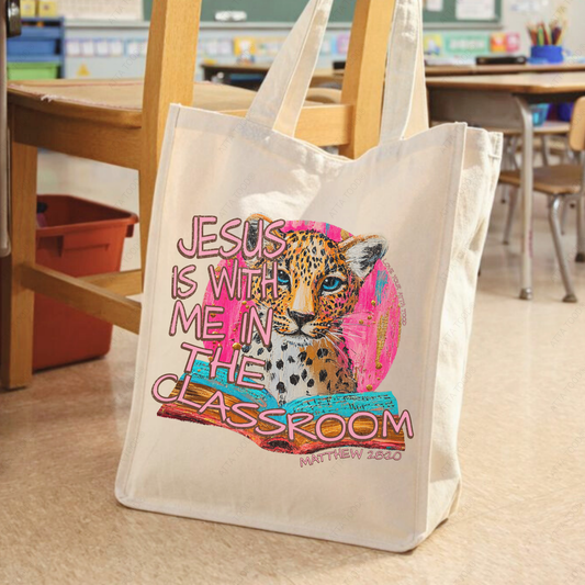 Jumbo canvas tote bag with “Jesus Is With Me in the Classroom” Christian teacher message, bold high-contrast painted-style graphic, Love your ATTA TOOD® brand mark, printed on both sides.