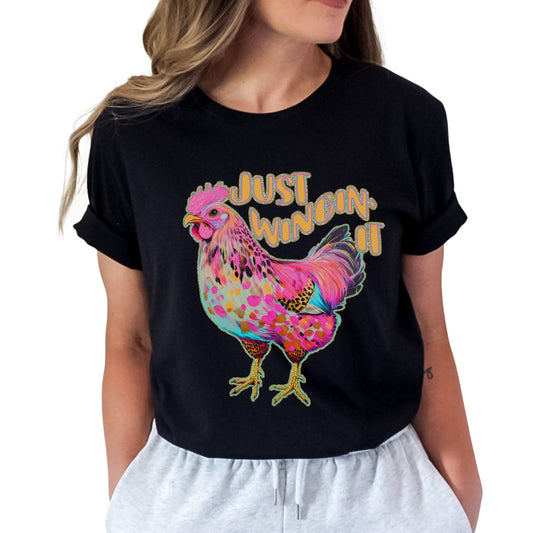 Black t-shirt with a colorful rooster graphic and 'Just Winin' It' text on a white background