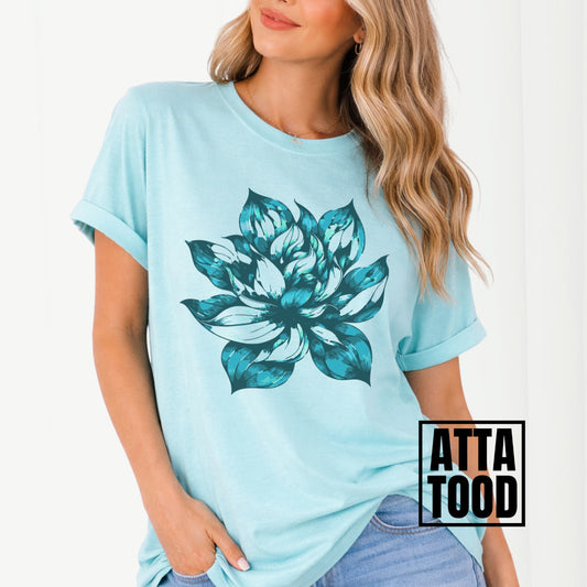 Light blue t-shirt with a large teal floral design worn by a person, with 'ATTA TOOD' branding.