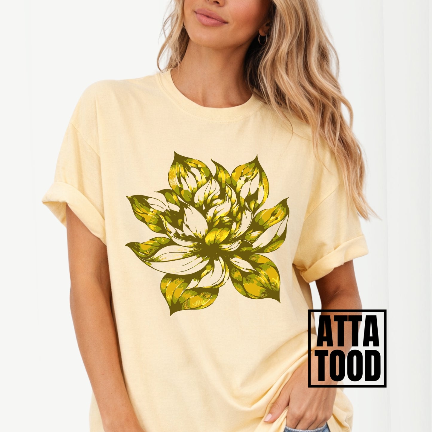 yellow t-shirt with a large yellow green floral design worn by a person, with 'ATTA TOOD' branding.