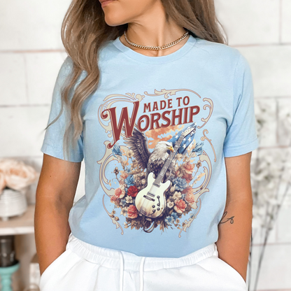 A person wearing a blue graphic t-shirt with the text 'MADE TO WORSHIP' and an image of a guitar and an Eagle.