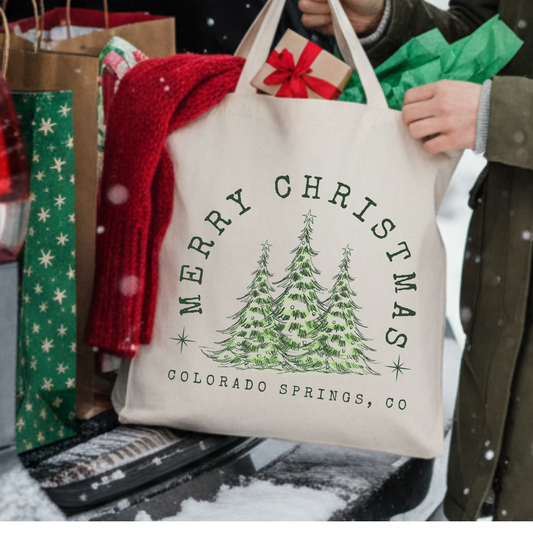 Canvas tote bag with 3 large green Christmas trees.  Tote bag says Merry Christmas. Customizable tote with business name, city and state or both