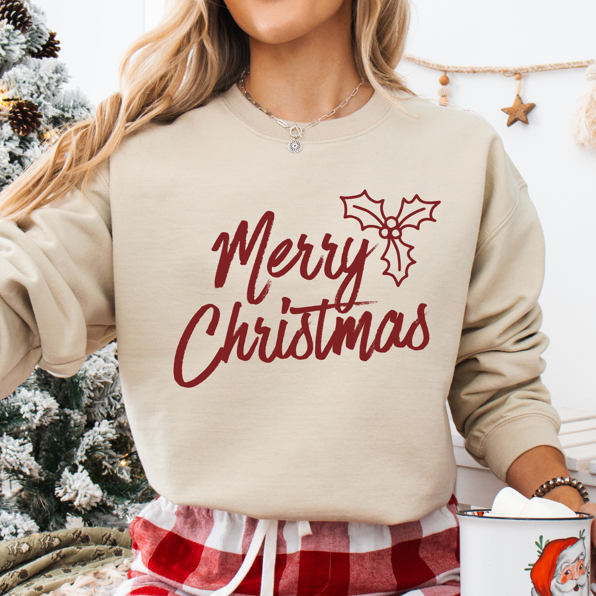 A classic Merry Christmas graphic with a simple holly detail for an easy, timeless holiday look on a beige sweatshirt