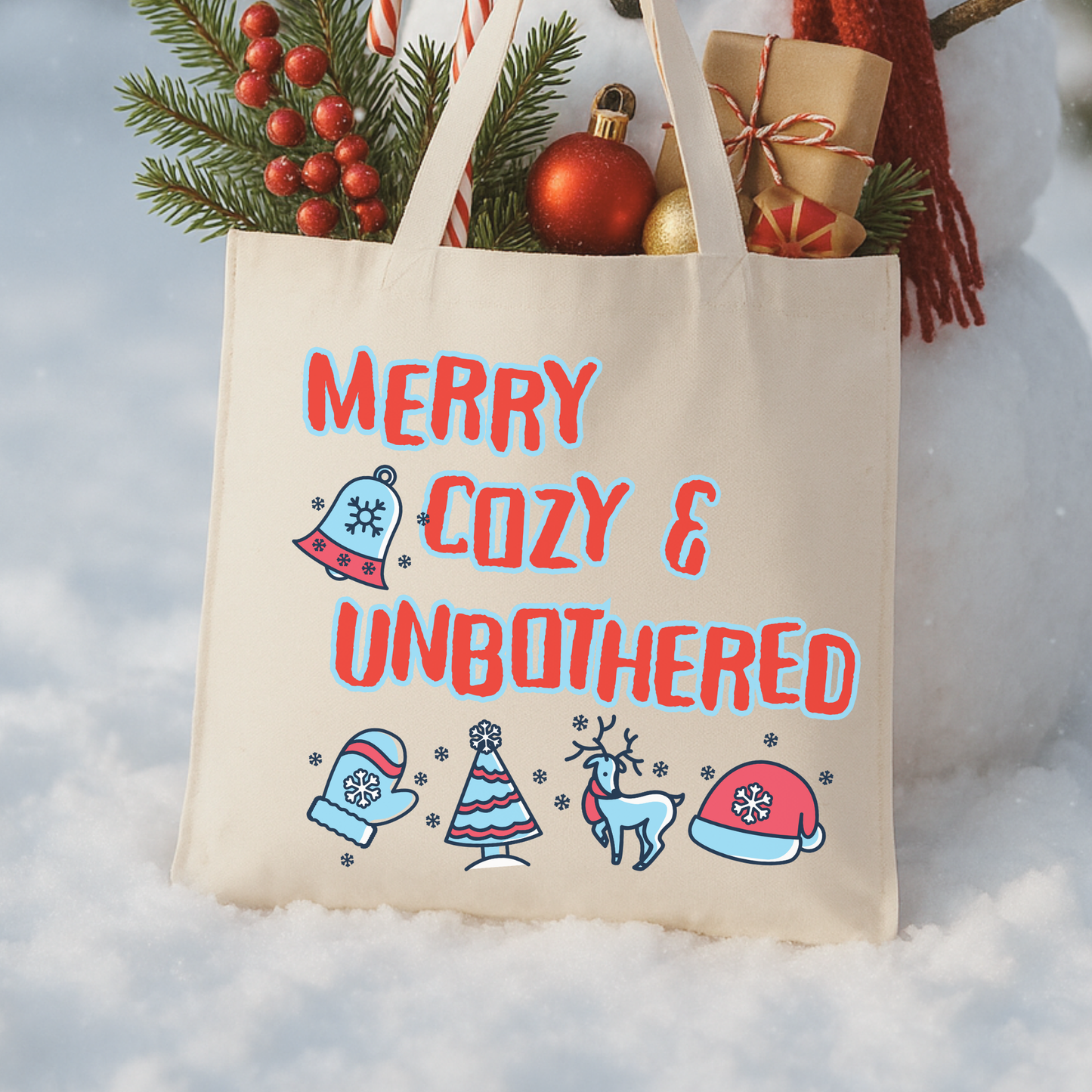 Tote bag with Christmas-themed design and 'Merry Cozy & Unbothered' text .  Red and light blue colors