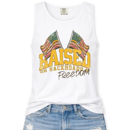 White tank top with colorful flag design and text 'Raised on Backroads and Freedom' on a white background.