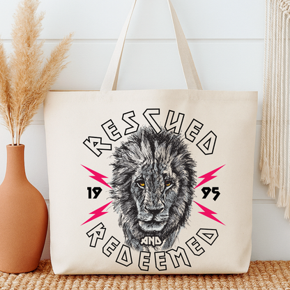 Tote bag with lion graphic and text 'Rescued and Redeemed 1995' on a neutral background