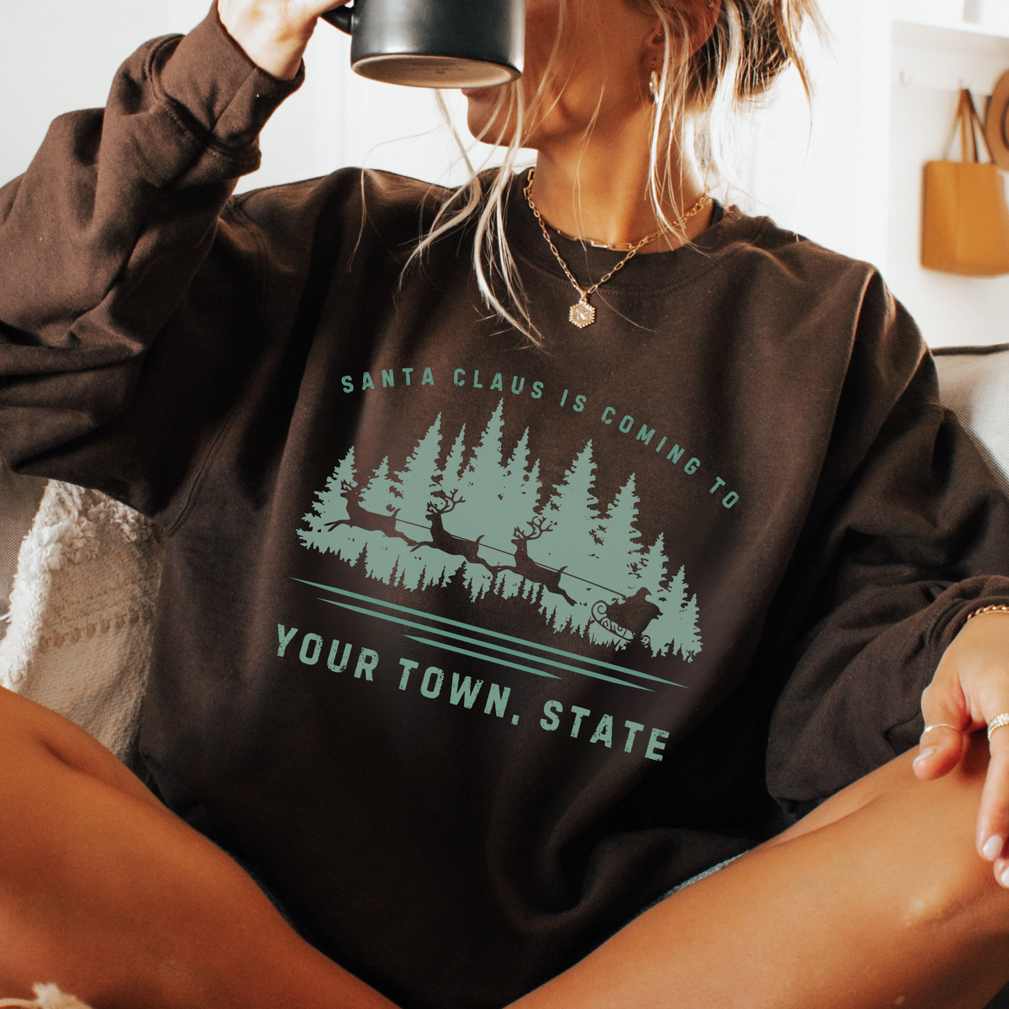 Custom Santa's coming to.  customize your city, state or business.  Santa's sleigh and reindeer flying over the forest on a dark brown sweatshirt.