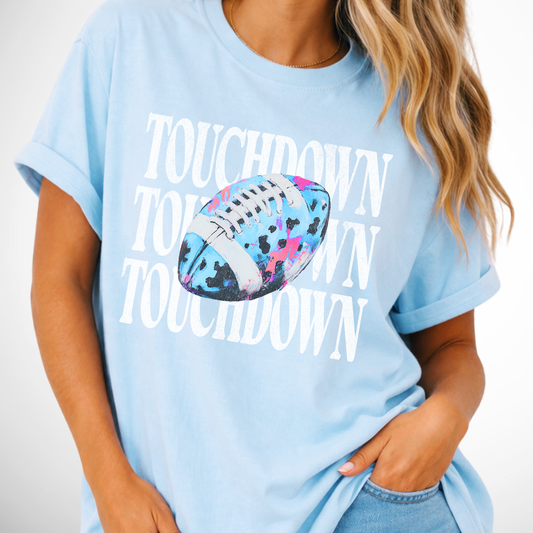 Touchdown three times with a neon blue football with splahes of pink and black on a chambray blue tee
