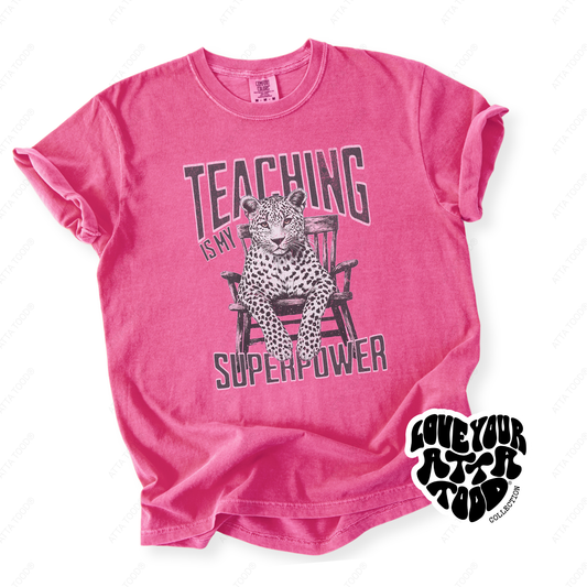 Leopard-print style graphic with teacher phrase “Teaching Is My Superpower,” high-contrast statement artwork with thick paint texture feel, printed on a Comfort Colors® tee.