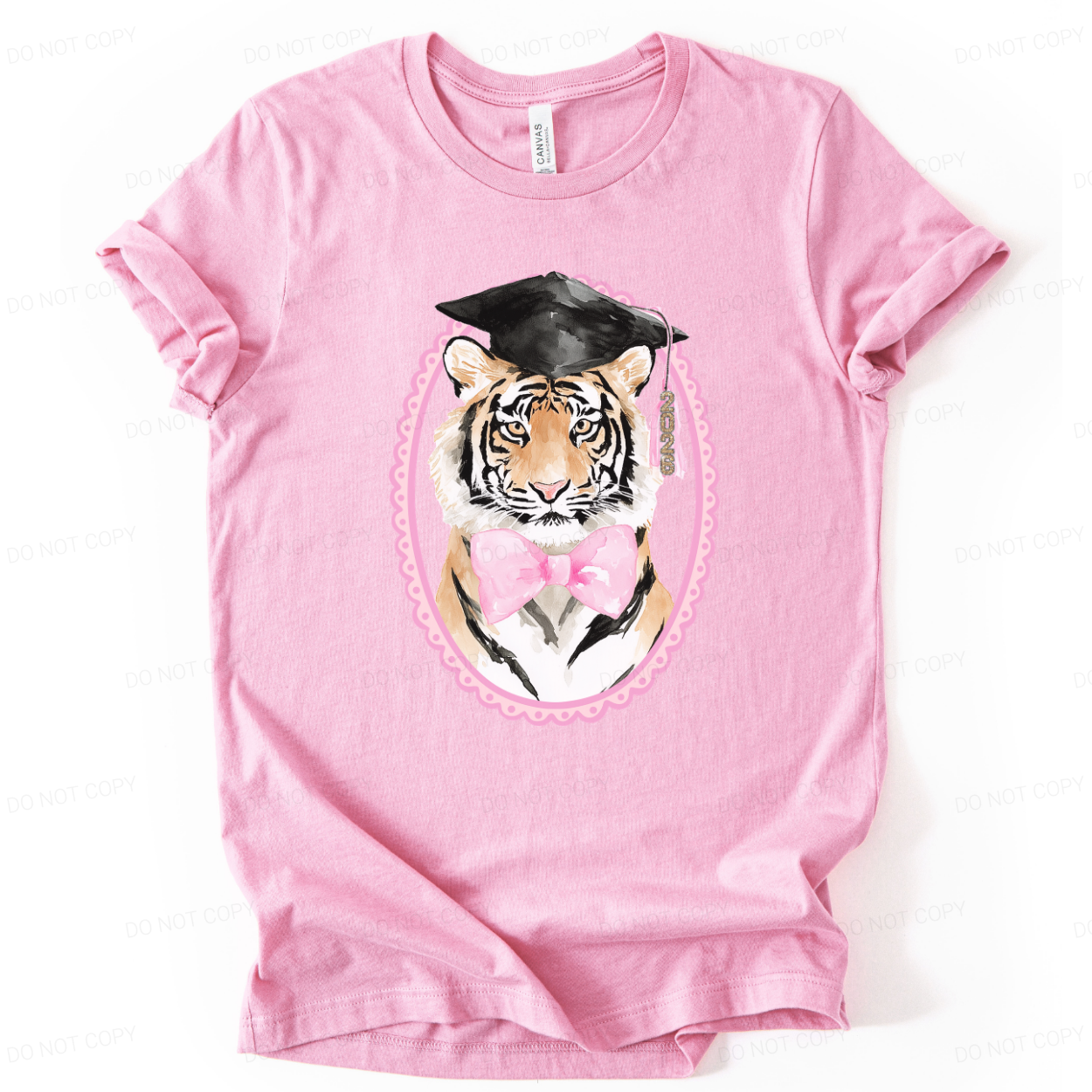 Graduation 2026 mascot themed graphic t shirt. The design features a detailed tiger portrait wearing a black graduation cap with a 2026 tassel, accented with a soft pink bow and framed in a decorative oval border. The combination of mascot styling and feminine pink accents creates a strong senior year statement with clear Class of 2026 visibility.