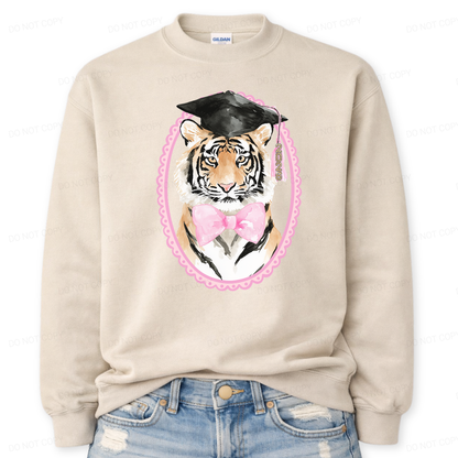Beige sweatshirt with a tiger wearing a graduation cap and pink bow tie design, paired with blue jeans.
