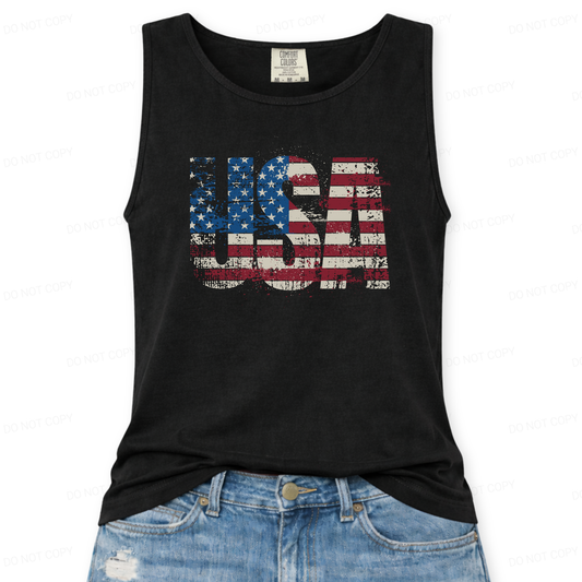 Distressed oversized "USA" overlayed with an American Flag on a Comfort Colors garment dyed unisex black tank top