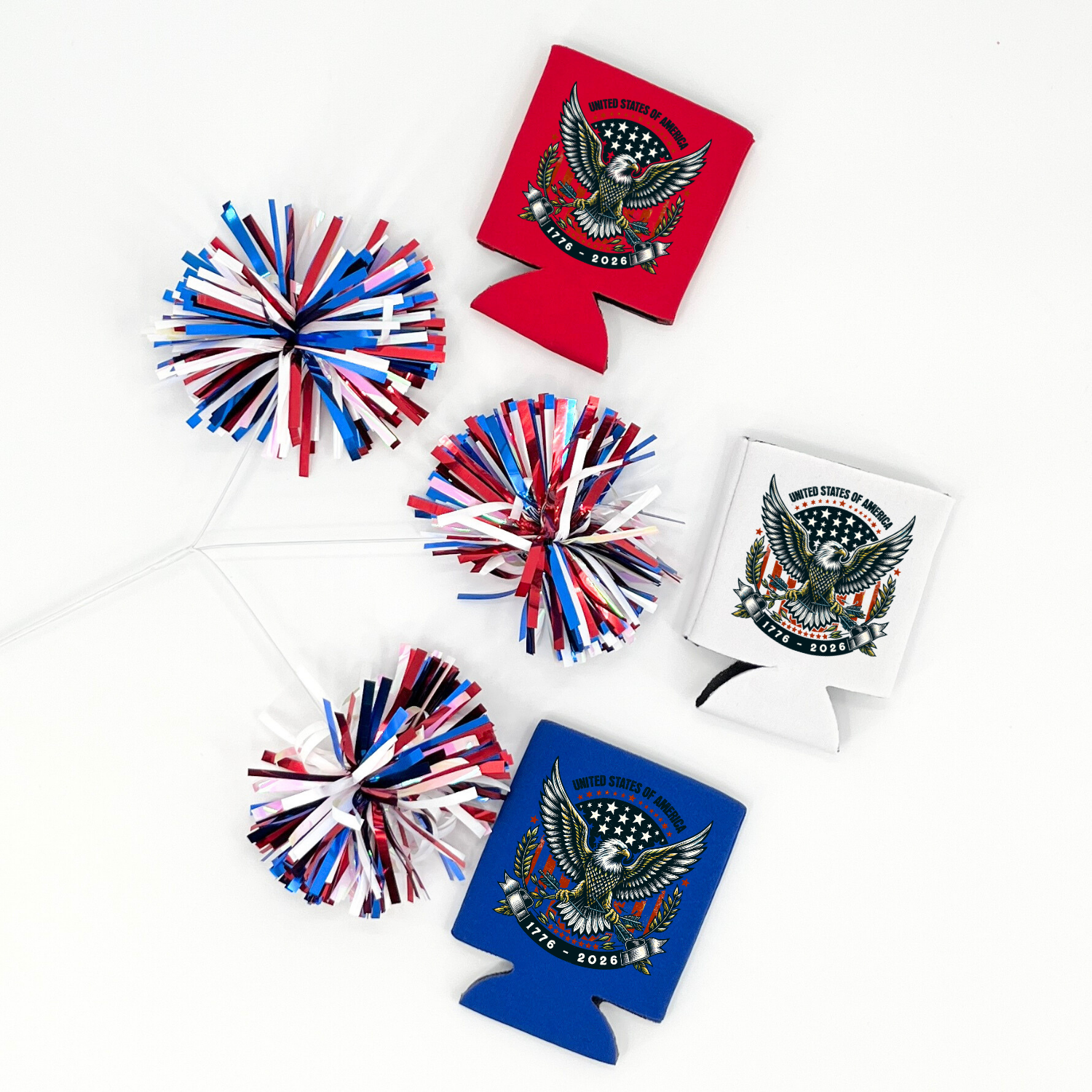 Assorted collapsible can coolers in red, white, and royal blue displayed with red, white, and blue metallic pom poms. The graphic features a bald eagle with patriotic stars and a crest reading “United States of America 1776–2026.” Patriotic design printed on the front of the drink sleeve style can coolers.