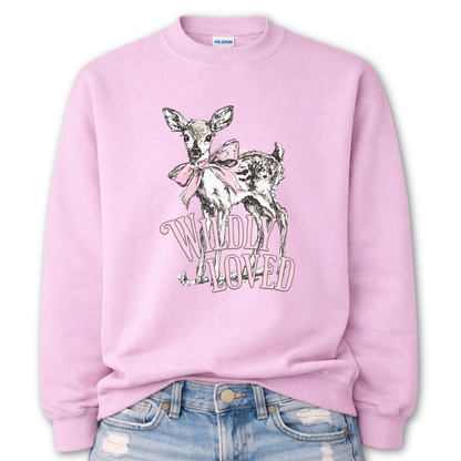 pink Bold Christian graphic on a Gildan crewneck sweatshirt. The design features a fawn with soft brown detailing and a large pink bow, paired with the phrase “Wildly Loved” in blush vintage-style lettering. 