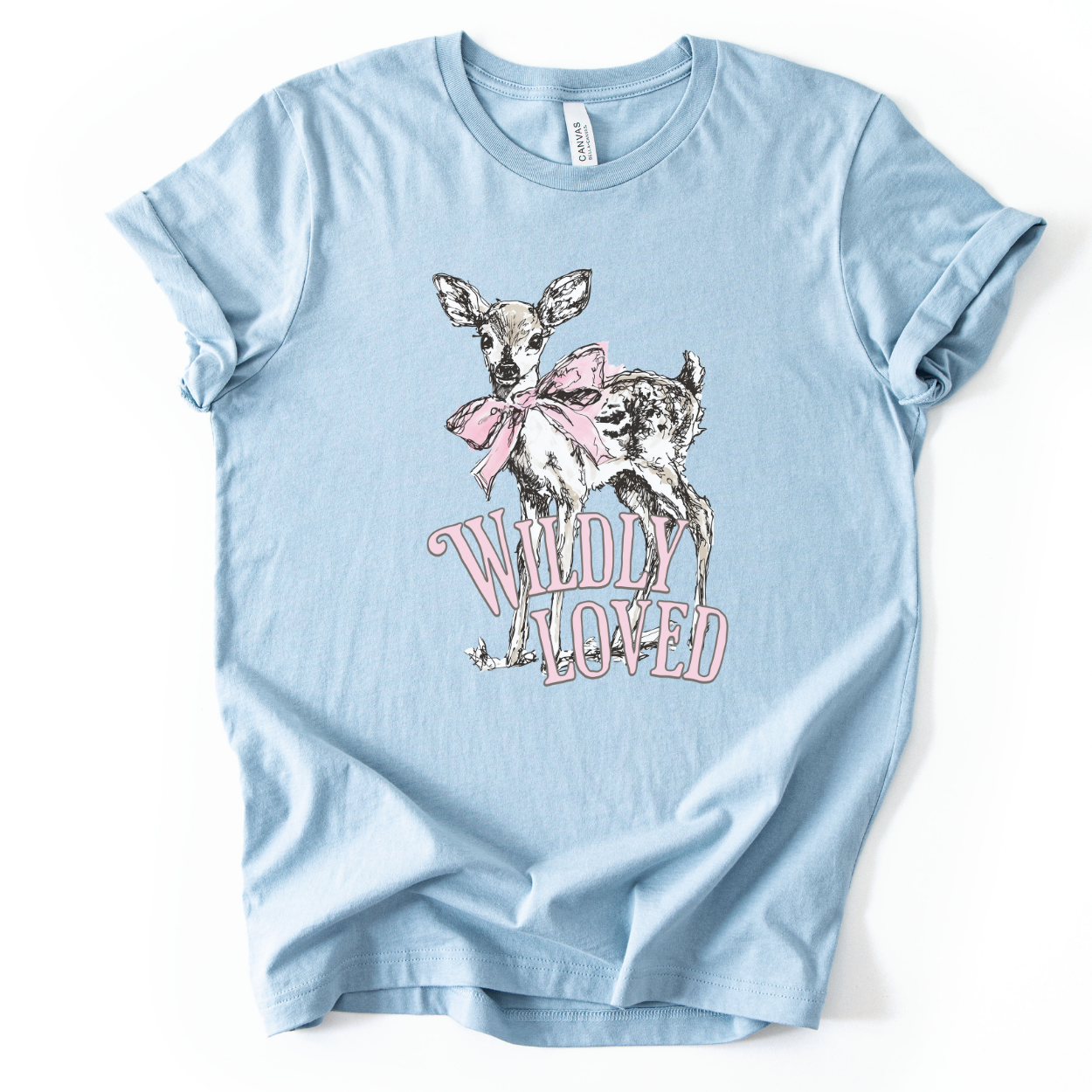 Christian spring cross graphic on a Bella Canvas t-shirt. The design features a greenery-filled cross adorned with a large pink bow, layered with the phrase “Hope Blooms Here” in bold, vintage-inspired lettering. The artwork blends Easter symbolism with soft feminine styling, creating a faith-forward seasonal piece.&nbsp;