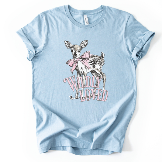 Christian spring cross graphic on a Bella Canvas t-shirt. The design features a greenery-filled cross adorned with a large pink bow, layered with the phrase “Hope Blooms Here” in bold, vintage-inspired lettering. The artwork blends Easter symbolism with soft feminine styling, creating a faith-forward seasonal piece.&nbsp;