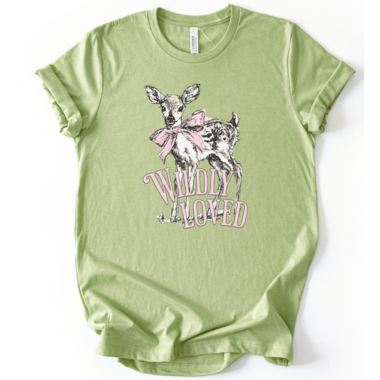 Christian spring cross graphic on a Bella Canvas t-shirt. The design features a greenery-filled cross adorned with a large pink bow, layered with the phrase “Hope Blooms Here” in bold, vintage-inspired lettering. The artwork blends Easter symbolism with soft feminine styling, creating a faith-forward seasonal piece.&nbsp;