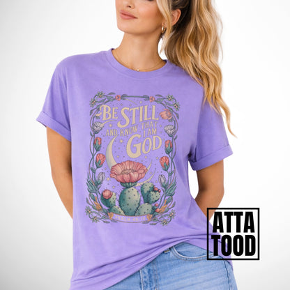 Be still and know that I am God Psalm 46:10 .  an oversized blooming cactus plant on  an violet comfort colors tee