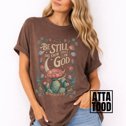 Be still and know that I am God Psalm 46:10 .  an oversized blooming cactus plant on  an brown comfort colors tee