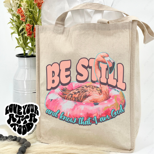Tote bag with flamingo graphic and text 'Be Still and know that I am God' on a white background